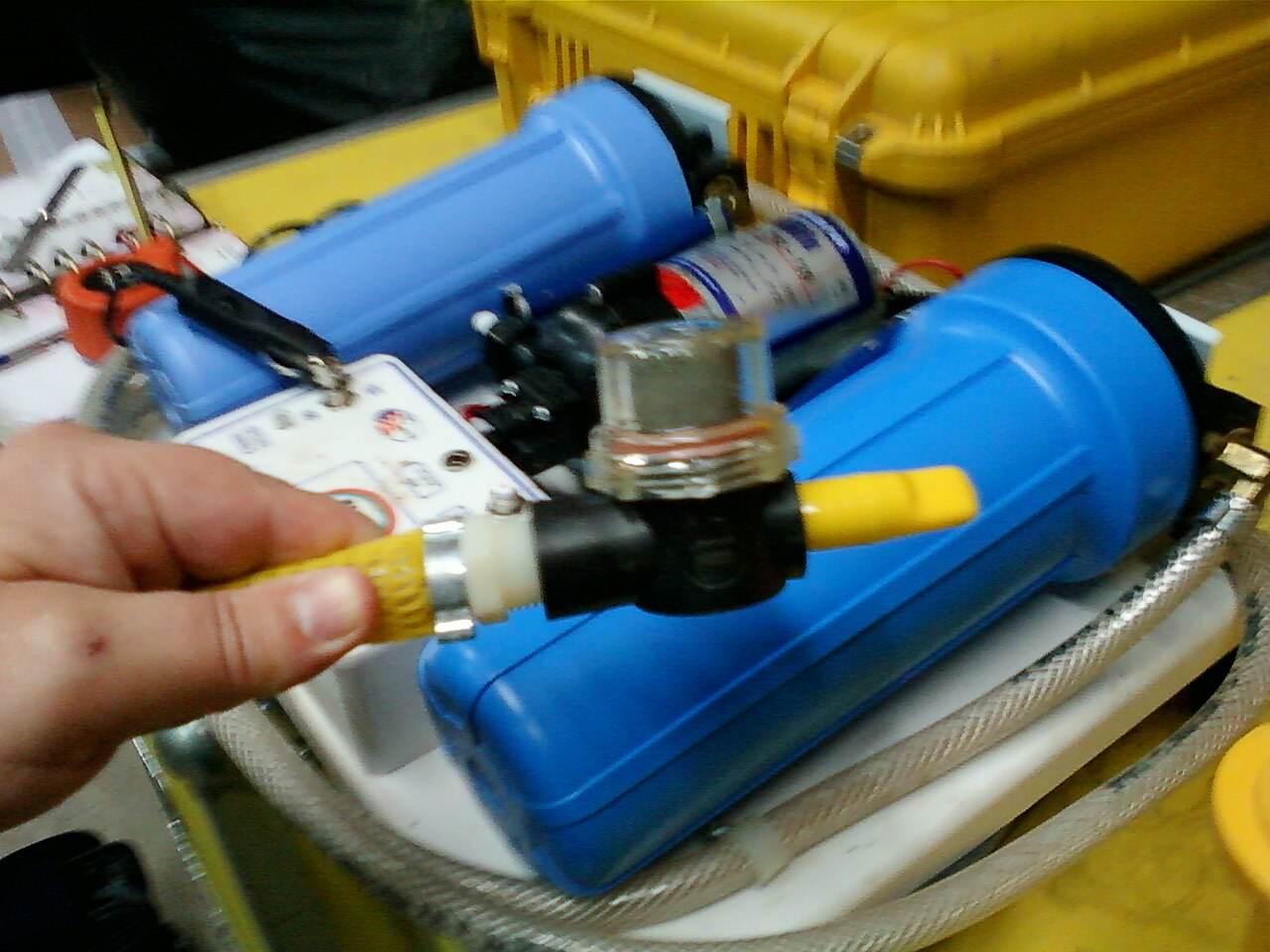 Flat lay of water treatment gear on a rock: bleach bottle, chlorine dioxide tablets and a squeeze filter